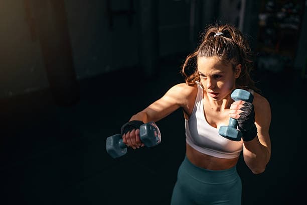 female-kickboxer-shadowboxing-with-dumbbells